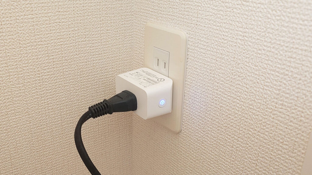 壁のコンセントに、上下逆向きに差したTapo P110M。電源ボタンが青く点灯し、DELTA 2 Maxの充電ケーブルが接続されている様子